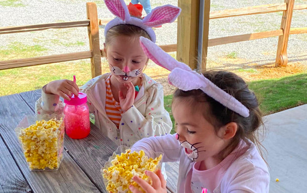 Sisters dressed as bunnies munch on popcorn - Spring into Easter