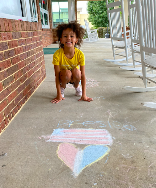 Dublin Visitor Center - Little girl squats behind chalk heart and flag on porch